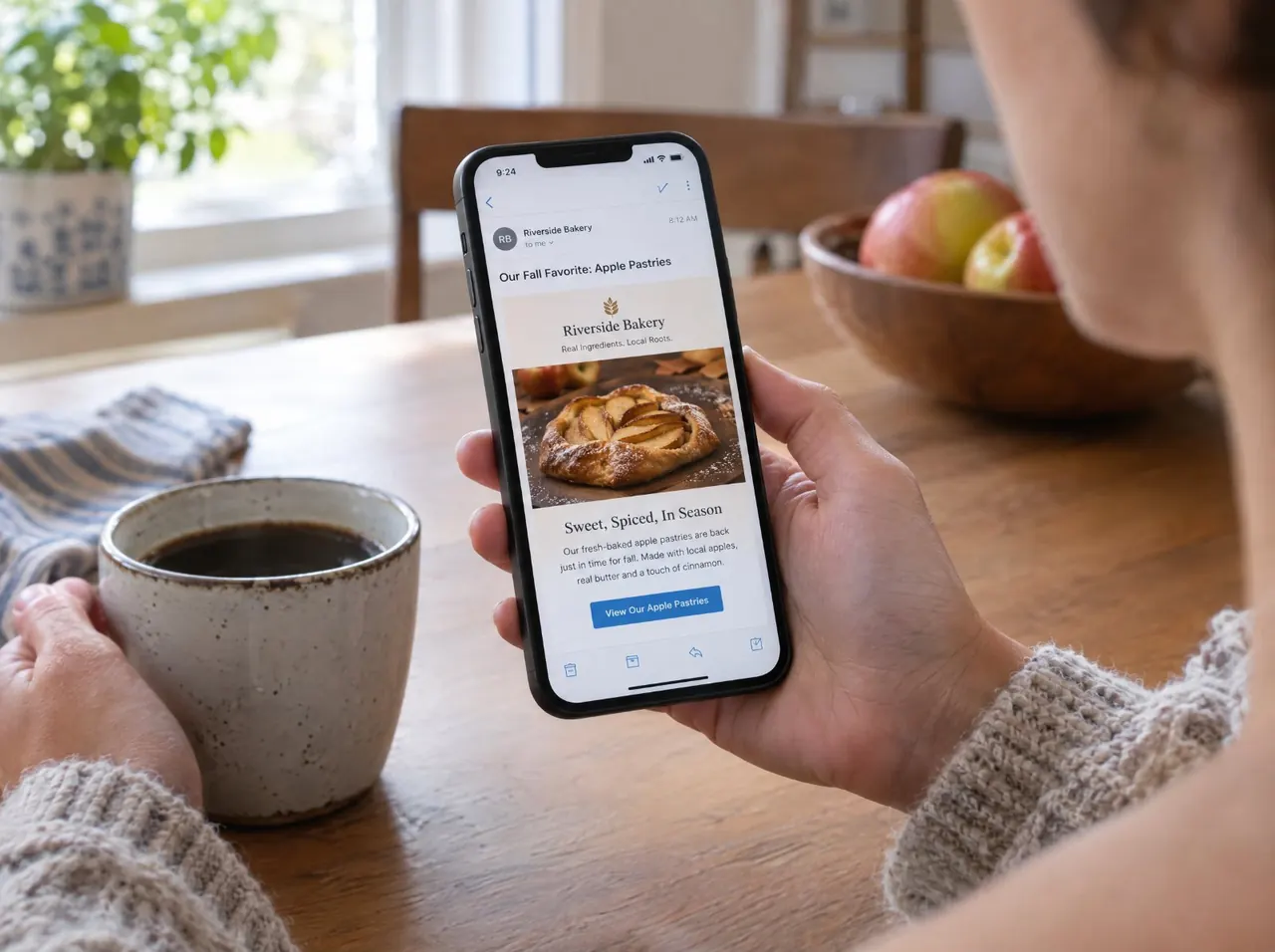 Person reading a bakery's email newsletter on a phone over coffee